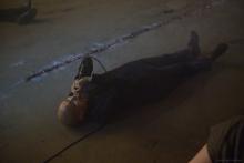 Dark image of Rajni lying on the ground with a microphone to their mouth