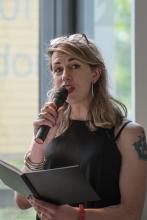 Emma Frankland, speaking into a microphone, book in hand